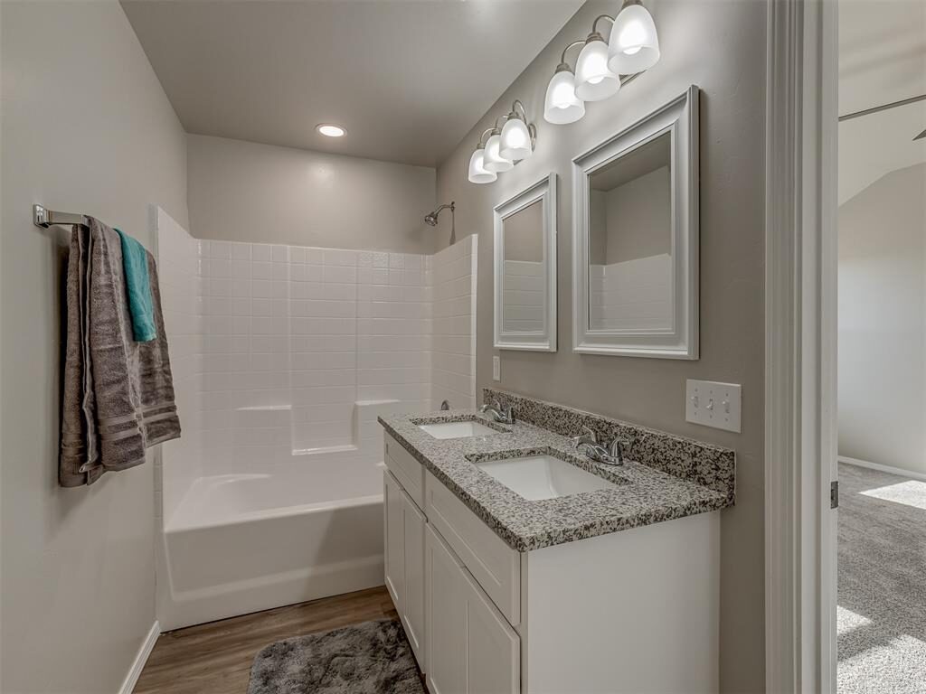 Shared bathroom with double sinks, framed mirrors, and tub surround