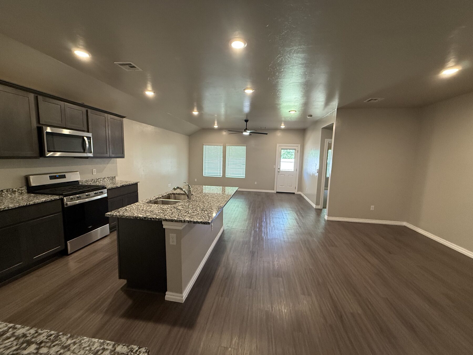 Finished kitchen and living area with white cabinetry and dark island