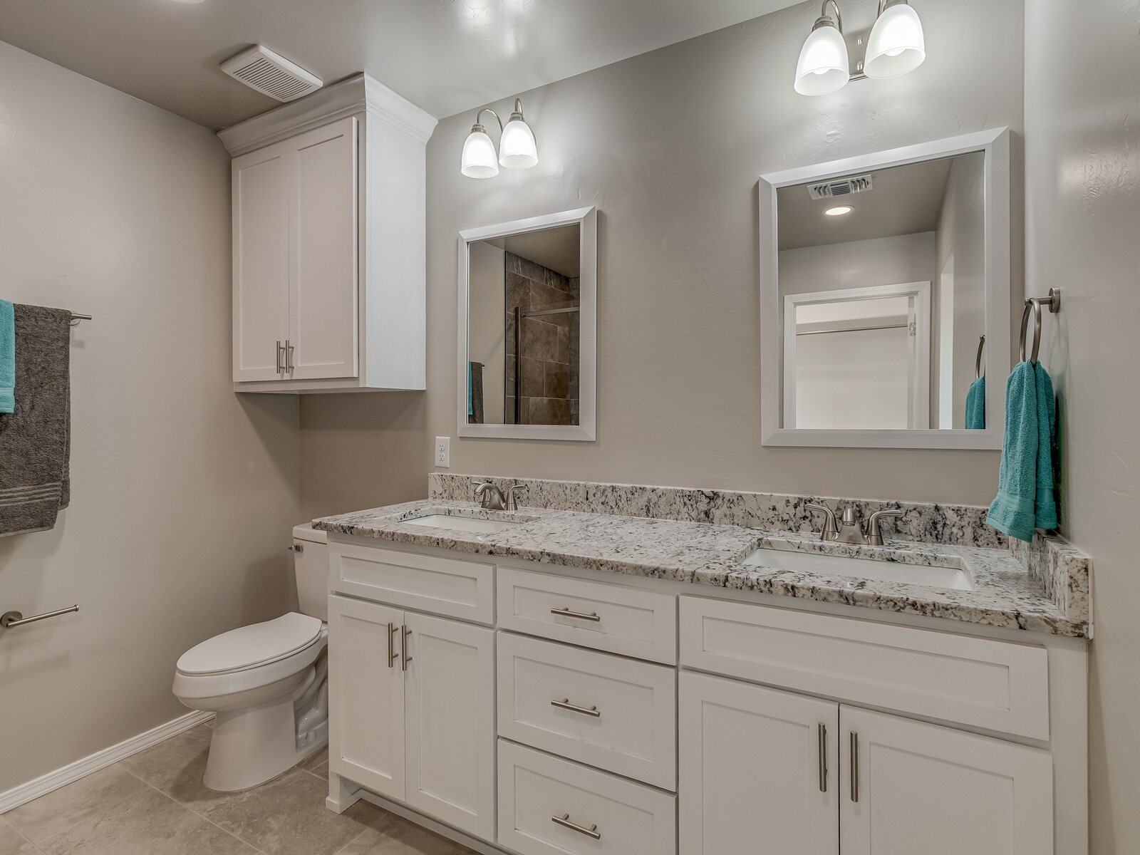 Finished bathroom with double vanity and white cabinetry